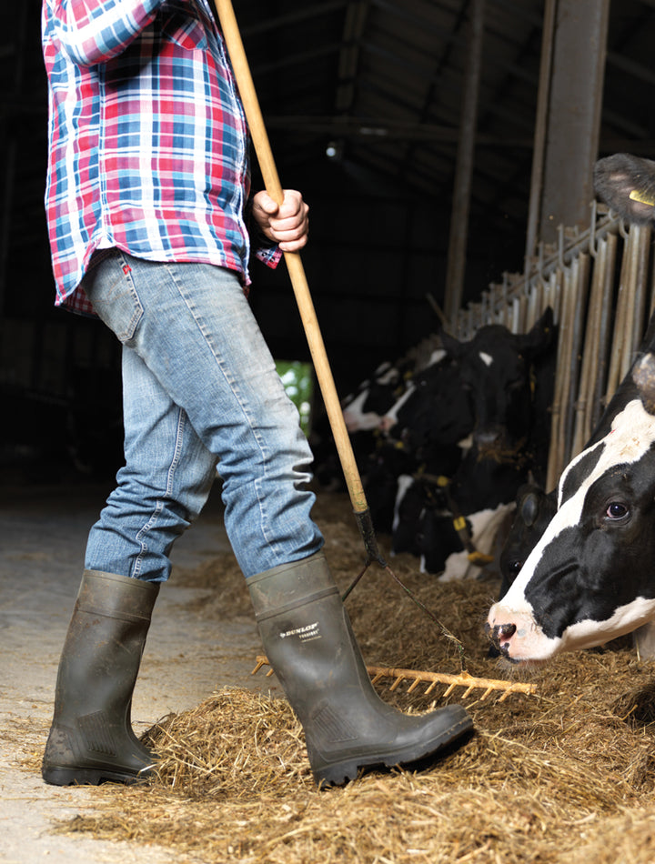Ganadero esparciendo paja para las vacas con las botas Dunlop Purofort Professional (Verde Oscuro/Negro)