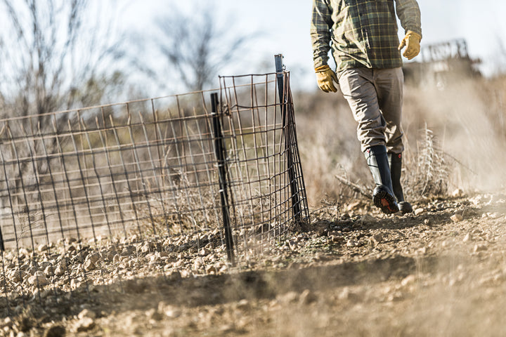 Agricultor sobre terreno con tierra y piedras con la bota Dunlop Purofort+ Full Safety (Verde Oscuro / Negro)