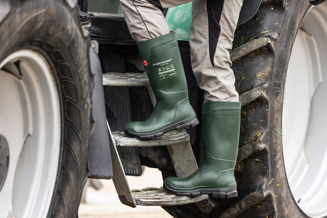 Agricultor subiéndose al tractor con las botas Dunlop Purofort TerraPRO Full Safety (Verde/Negro)