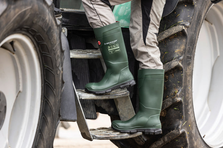 Agricultor subiéndose al tractor con las botas Dunlop Purofort TerraPRO Full Safety (Verde/Negro)