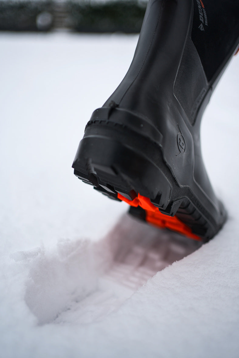 Bota Dunlop Snugboot Heavy Duty Calf Full Safety Media Caña para Trabajos Pesados pisando la nieve