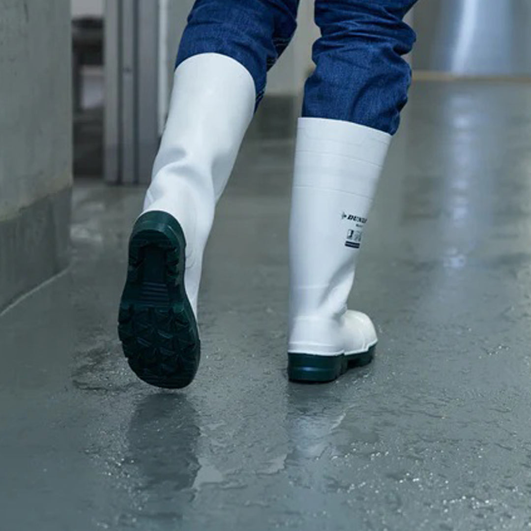 Botas Dunlop Work-It S4 (Blanco) calzadas con la suela a la vista sobre suelo mojado en zona alimentaria