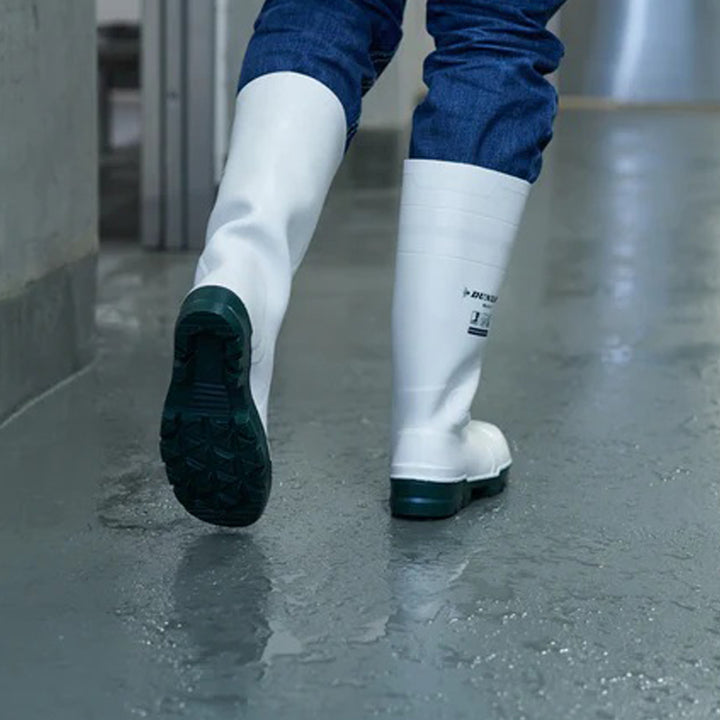 Botas Dunlop Work-It S4 (Blanco) calzadas con la suela a la vista sobre suelo mojado en zona alimentaria