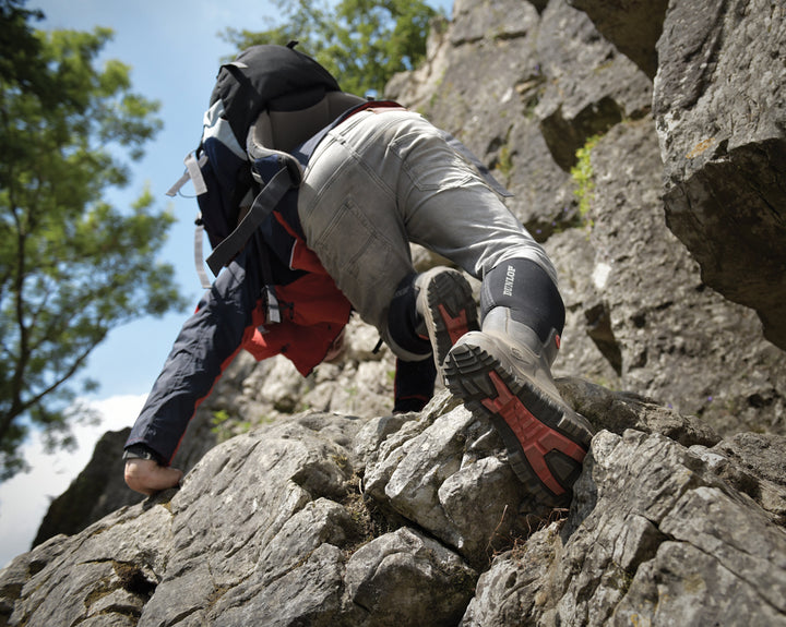 hombre subiendo por las rocas con las botas Dunlop Snugboot Pioneer